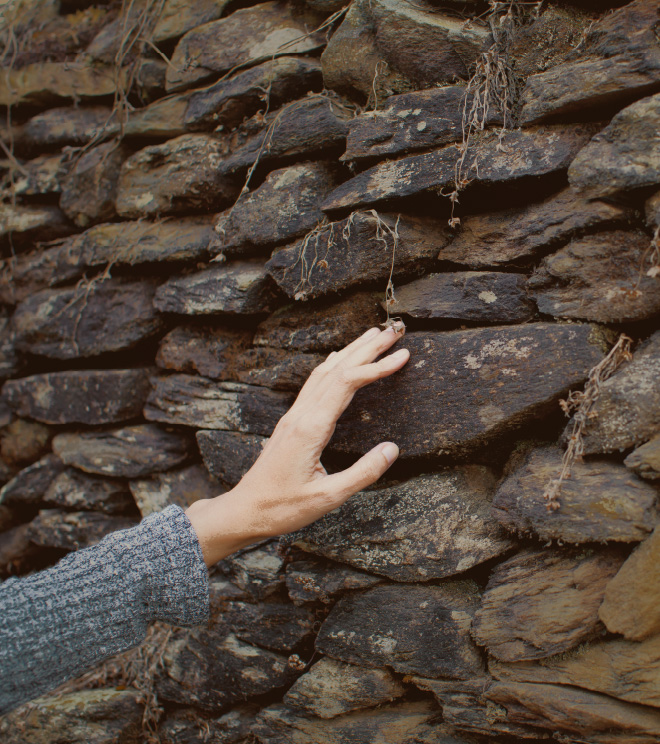 mano tocando muro de piedra